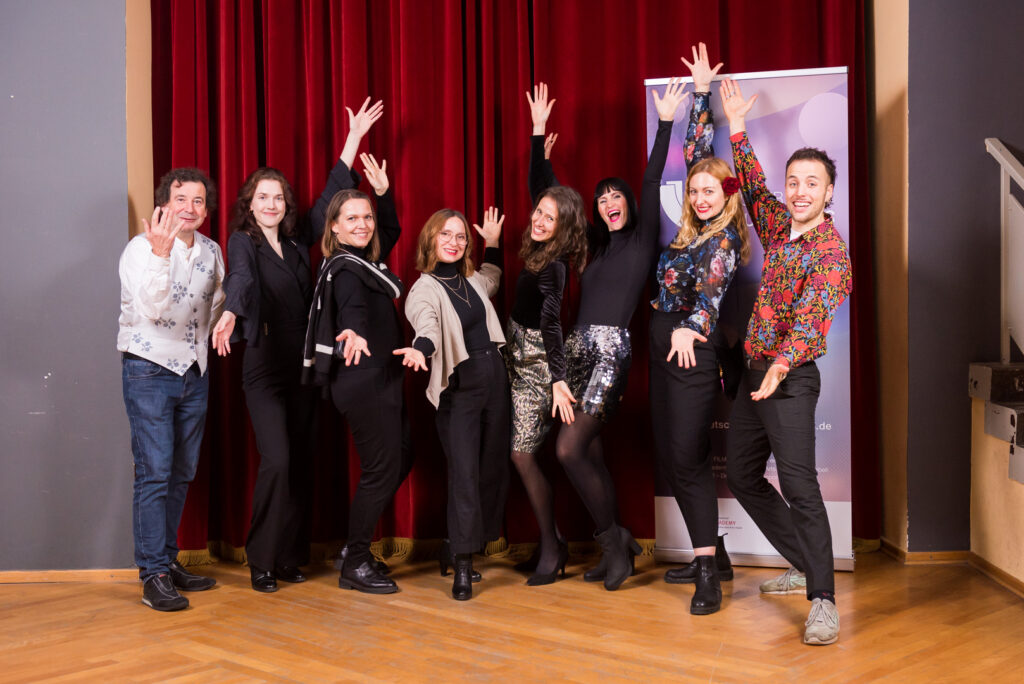 Musikland Blog 28 Ein Gruppenfoto. Die Personen sind festlich gekleidet und in einer feierlichen Geste fotografiert.